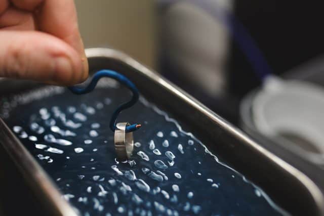 Goldsmith's Hand Cleaning A Ring Using An Ultrasonic Cleaner.